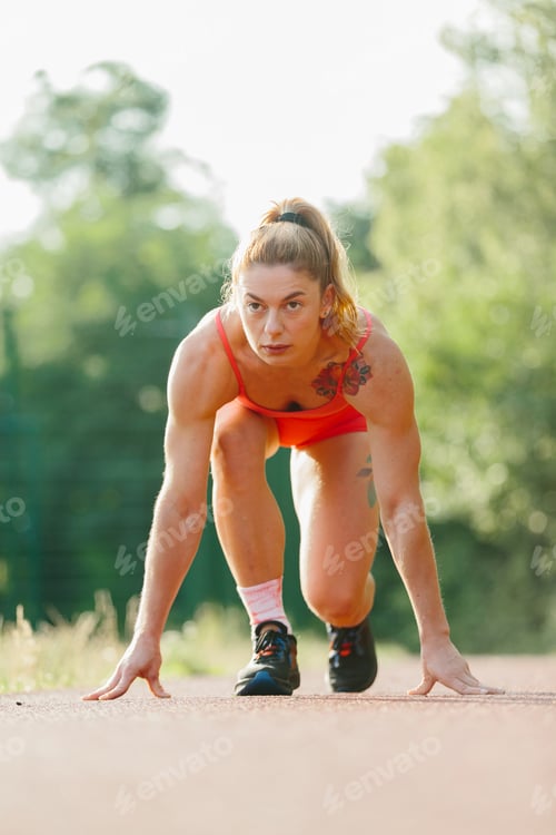 Preview: Woman preparing for track start on running path