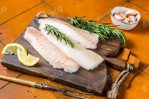 Preview: Raw cod fish fillets, codfish with rosemary on wooden board. Orange background. Top view