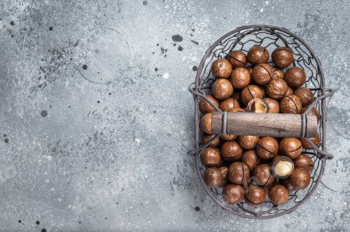 Preview: Macadamia organic nuts in a basket. Gray background. Top view. Copy space