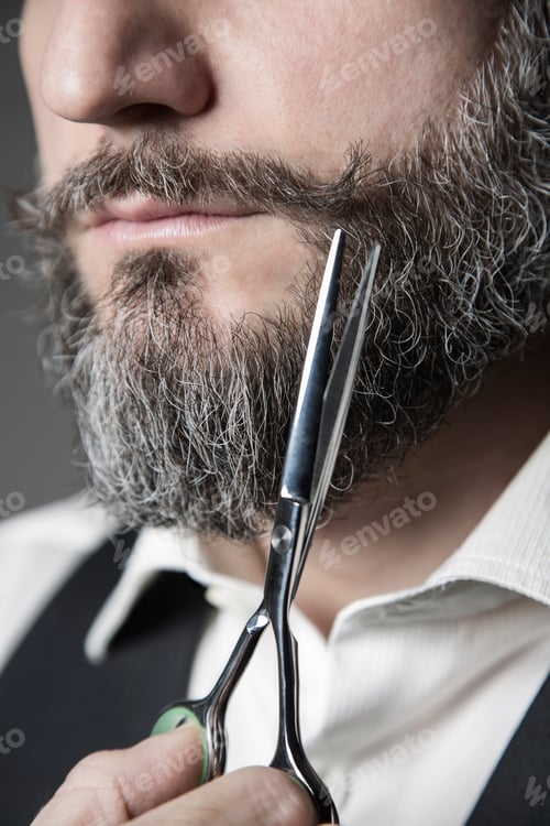 Preview: close up of a barber adjusting his mustache with a pair of sciss