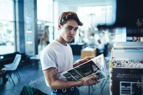 Preview: Serious male reading book in light room