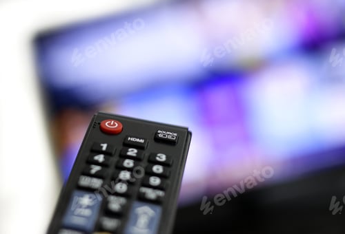 Preview: Closeup shot of a person holding a black remote control in front of the TV