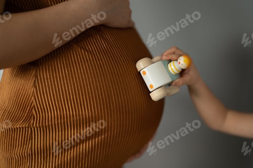 Preview: Little girls hand drives a toy on mom baby tummy