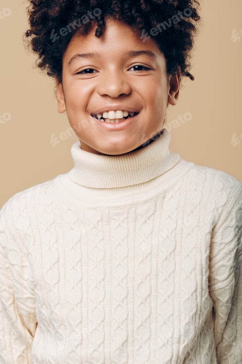 Preview: Young african american boy with bright smile wearing a white turtleneck sweater against a soft beige