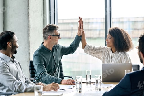 Preview: Happy international business people giving high five at meeting room table.