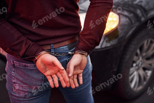 Preview: Woman standing in handcuffs near modern automobile outdoors