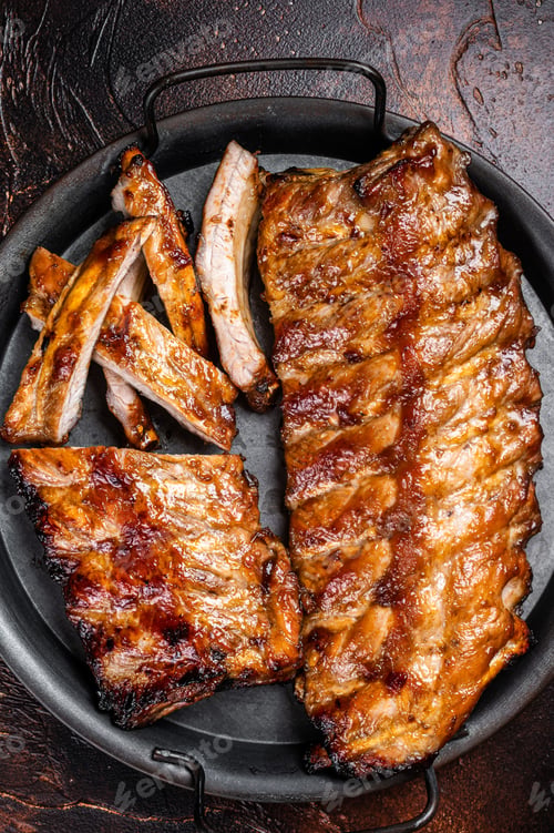 Preview: BBQ pork spare ribs St Louis with hot honey marinade in a steel tray. Dark background. Top view