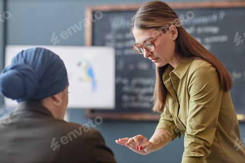 Preview: Female Teacher Explaining Task to Woman Helping Student in Class at School