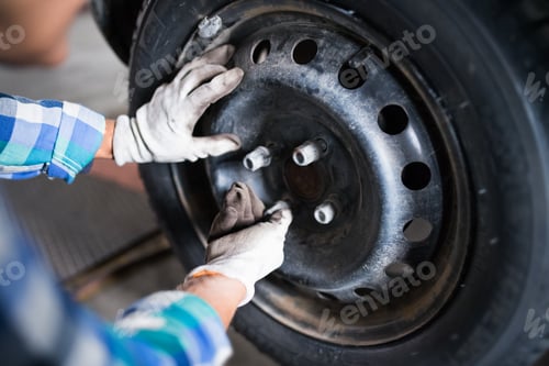 Preview: Senior female mechanic repairing a car in a garage.
