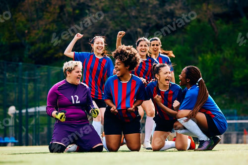 Preview: Happy female players celebrating victory after soccer match at the stadium.