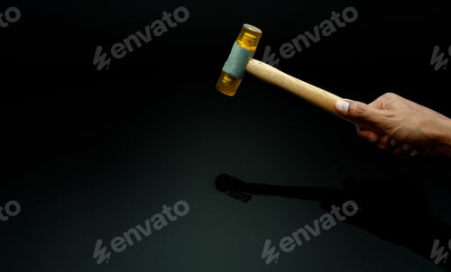 Preview: Man's hand holding plastic hammer isolated on dark background. Male worker's hand hold wood handle