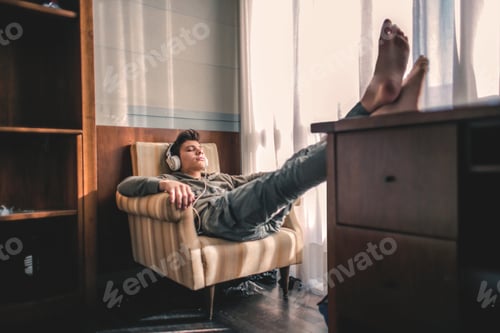 Preview: Boy with a grey outfit chilling in his room and listening to music with his white headphones