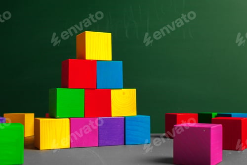 Preview: Colorful wooden blocks stacked and arranged in a playful setting for children near a chalkboard