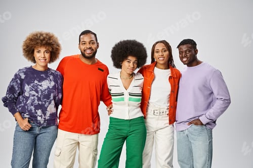 Preview: cheerful african american woman hugging her friends in vibrant attire on grey background, Juneteenth