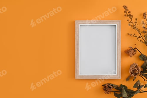 Preview: Wooden picture frame and dried flowers on yellow background. Flat lay, top view, copy space.