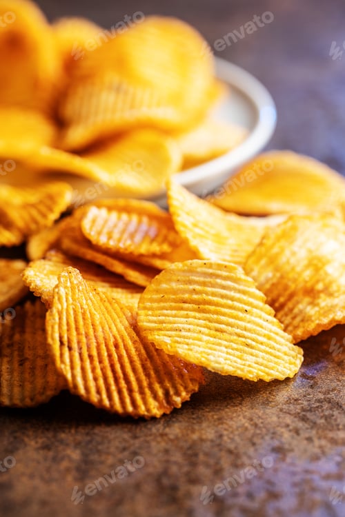 Preview: Crispy potato chips on brown table.