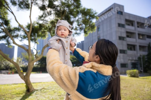 Preview: Loving mother lifting baby in outdoor park