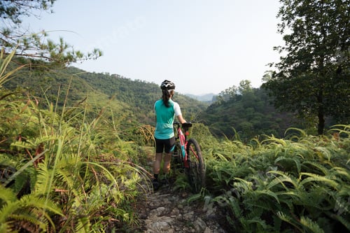 Preview: Woman mountain biker looking at the view on mountain top