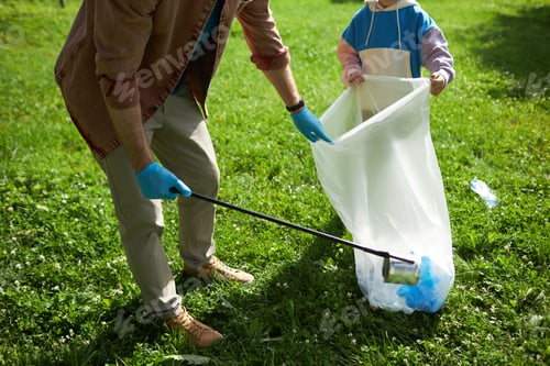 Preview: Father and son picking up trash outdoors helping clean nature in sunlight