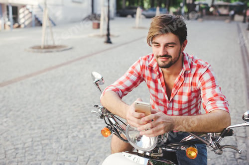 Preview: Smiling young man texting on the cellphone