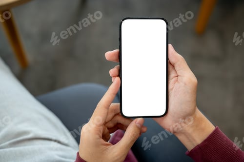 Preview: A man's hands holding blank screen smartphone with both hand while sitting indoor at cafe or library
