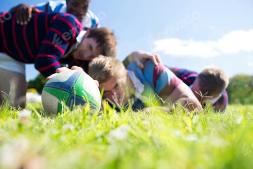 Preview: Close up of men playing rugby while lying at grassy field