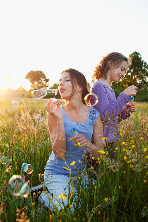 Preview: Sisters blowing bubbles in field