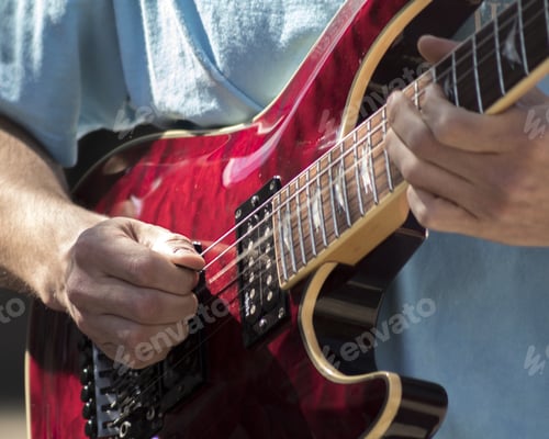 Preview: Closeup of a man's hands playing a red electric guitar