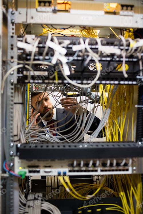 Preview: Technician talking on mobile phone while checking cables