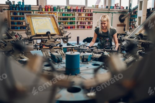 Preview: Print shop worker operating screen carousel printing machine at workshop