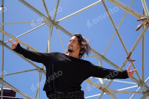 Preview: Young hispanic latin street dancer with blue sky background and metal structure