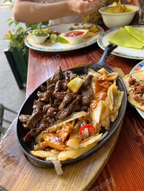 Preview: Meat with cabbage in a pan on a stand stands on a table in a restaurant