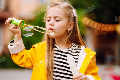 Preview: Cute little girl in the autumn on a walk blowing soap bubbles. Childhood, active rest, lifestyle.