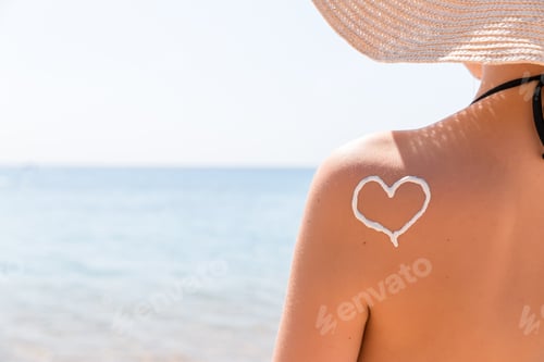 Preview: Heart made of sun cream is drawn on woman's shoulder at the beach