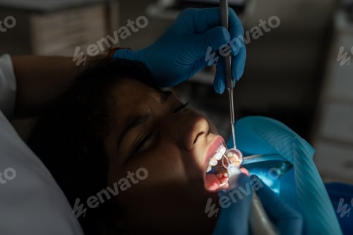 Preview: Woman in pain at dental clinic while doctor treating her