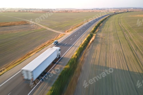 Preview: Aerial view of blurred fast moving semi-truck with cargo trailer driving on highway hauling goods in