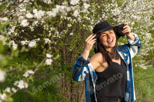 Preview: Portrait of a stylish girl among flowering trees in the forest.