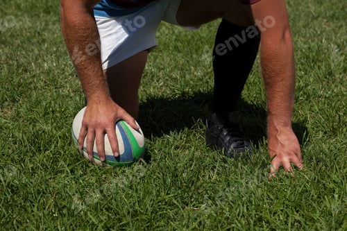 Preview: Player crouching with rugby ball on field