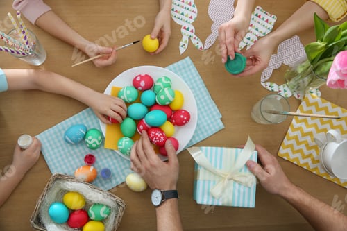 Preview: Family with colorful Easter eggs at table, top view