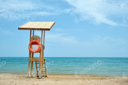 Preview: Emplty wooden lifeguard station on sandy beach on ocean shore in summer