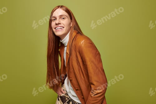 Preview: Emotional young man with long red hair expresses joy in a vibrant setting