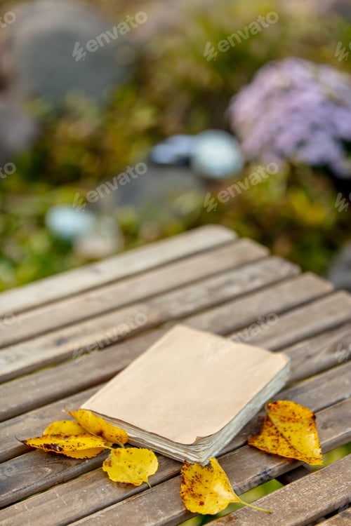 Preview: old book on a table in the garden in autumn
