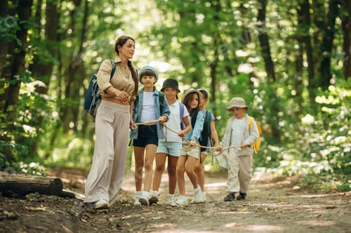 Preview: Knot in hands, for support. Woman is doing tour for group of kids in the forest