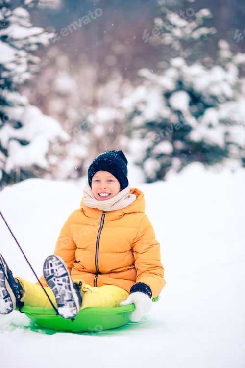 Preview: Adorable little happy girl sledding in winter snowy day
