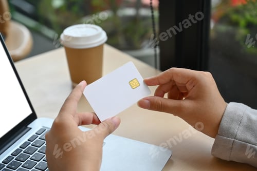 Preview: Close up female hands holding credit card and using laptop doing secure payment or shopping