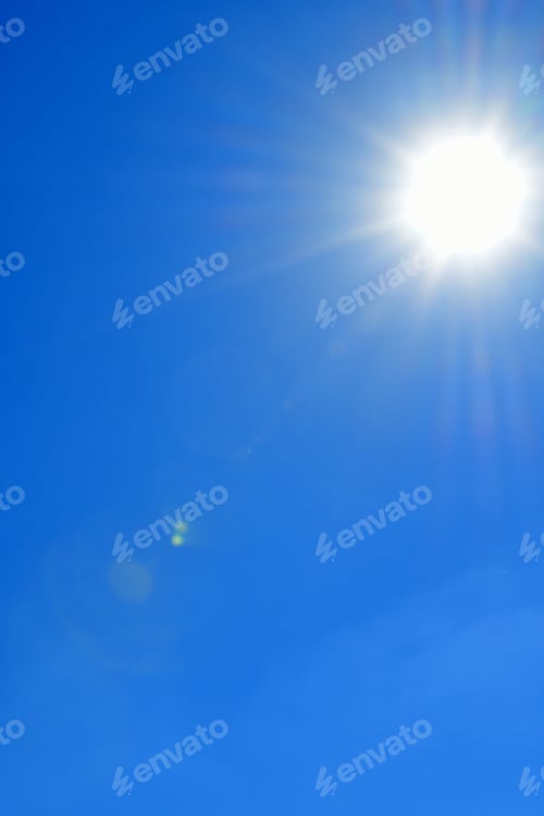 Preview: A vivid blue sky with the sun shining giving off sunbursts and sun flares with a few wispy clouds.