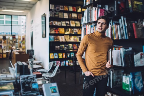 Preview: Thoughtful man with laptop standing in library