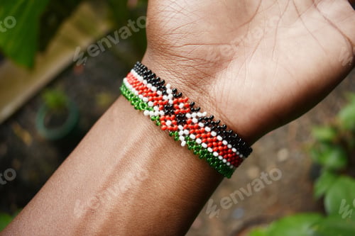 Preview: High angle shot of a person wearing a handmade bracelet of the Kenyan flag