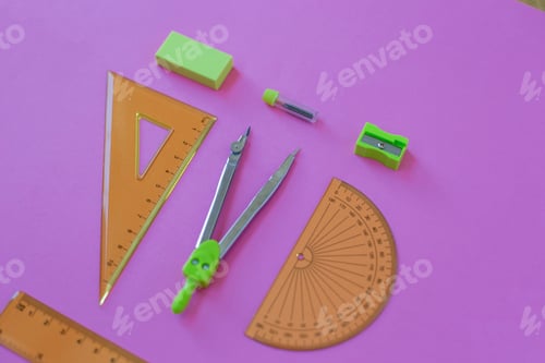 Preview: set of green geometry tools: rulers, compasses, eraser and sharpener lie on a pink background