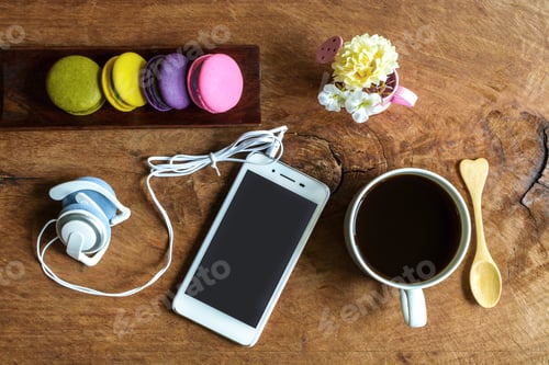 Preview: Colorful macaroons and a cup of coffee with cellphone on wooden